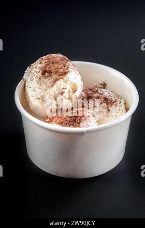 Köstliches Eis in der Papierschale auf schwarzem Hintergrund. Stockfoto