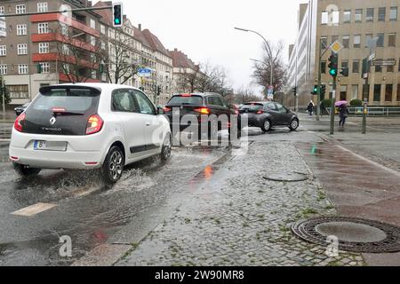 21.12.2023, Berlin, DE - Autos biegen an einer Strassenkreuzung nach rechts ab. Abbiegen, Alltag, Ampel, Ampelanlage, aussen, Aussenaufnahme, Autofahrer, Automobil, Autos, Autoverkehr, Berlin, Deutsch, Deutschland, Europa, europaeisch, Fahrbahn, Fahrzeuge, Fussgaenger, Gesellschaft, Individualverkehr, Jahreszeit, Kfz, Knobelsdorffstraße, Königin-Elisabeth-Straße, Kraftfahrzeuge, Menschen, Naesse, nass, Passanten, Personen, Personenkraftwagen, Pfuetze, PKW, QF, Querformat, Rechtsabbieger, Regen, Regenwetter, regnerisch, Schlechtwetter, Stadt, Stadtansicht, Stadtbild, Stadtleben, Stadtverke Stockfoto