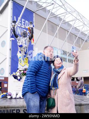 Die Fans posieren für ein Foto neben der Billy Bremner Statue vor dem Sky Bet Championship Match in der Elland Road, Leeds. Bilddatum: Samstag, 23. Dezember 2023. Stockfoto