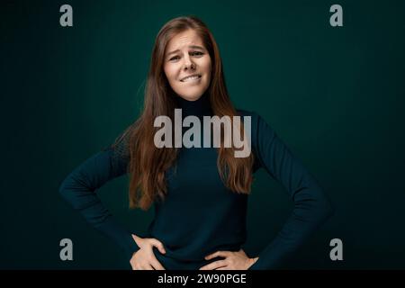 Kaukasische junge Frau mit grünem Rollkragen auf dunklem Hintergrund mit Kopierraum Stockfoto
