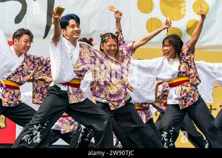 Das japanische Yosakoi-Tanzteam in Yukata-Tuniken auf der Bühne tanzt mit schwarzem Banner, das beim Krusyu Gassai-Festival in Kumamoto hinter sich gezogen wird. Stockfoto