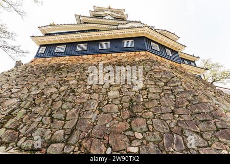 Flacher Blick auf den schwarz-weißen Donjon im Sotogata-Stil von Okayama Castle, der über der Spitze der in ishigaki-Tönen gehaltenen Wand thront. Stockfoto