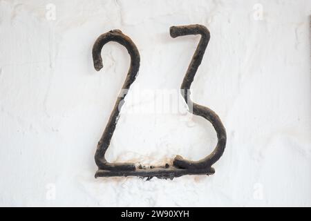 Altes verwittertes Haus Nr. 23, Metall an der Wand Stockfoto