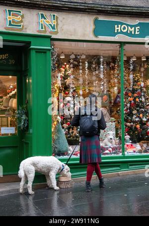 Edinburgh, Großbritannien. Dezember 2023. Ein Mann in einem Kilt schaut mit seinem Hund in einem Schaufenster in Edinburgh. Credit: Thomas Faull/Alamy Live News Stockfoto