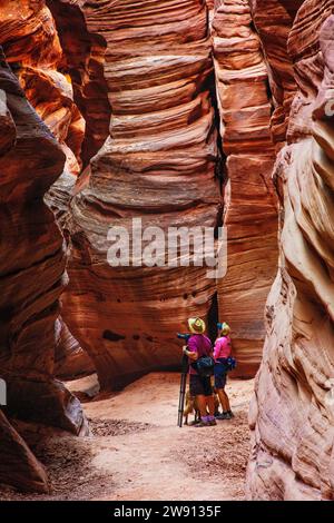 Ein Paar hält seine Wanderung an, um das Innere des Buckskin Gulch im Süden Utahs zu bewundern und zu fotografieren. Stockfoto