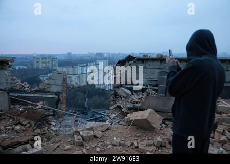 Kiew, Ukraine. Dezember 2023. Ein Mann filmt mit seinem Handy ein Video über die Schäden am Ort eines Drohnenangriffs auf ein Wohngebäude in Kiew. Mindestens zwei Menschen wurden verletzt, nachdem ein russischer Drohnenangriff zum dritten Mal ein Wohngebäude in Kiew getroffen hatte. Russlands Drohne vom Typ 'Shahed' traf ein Wohngebäude in der ukrainischen Hauptstadt. (Foto: Oleksii Chumachenko/SOPA Image/SIPA USA) Credit: SIPA USA/Alamy Live News Stockfoto