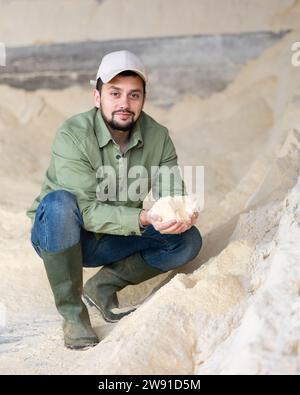 Porträt eines Bauern, der auf einem Maismehlhaufen hockt Stockfoto