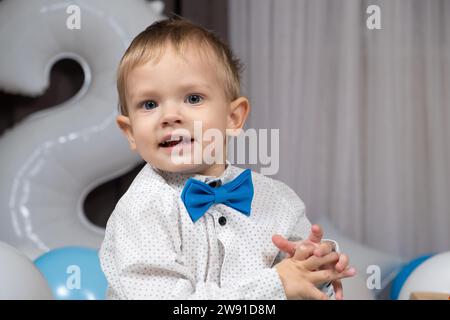 Porträt eines kleinen blonden Jungen mit blauen Augen, der ein Hemd mit Fliege trägt Stockfoto