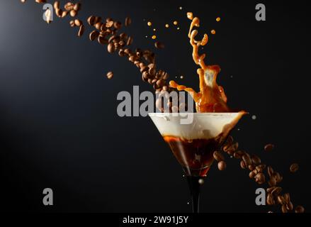 Espresso Martini-Getränk mit Spritzern und fallenden Kaffeebohnen auf schwarzem Hintergrund. Kopierbereich. Stockfoto