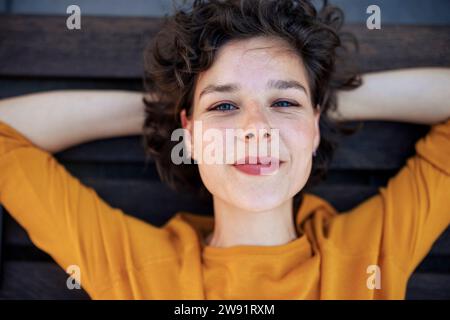 Lächelnde Frau mit Händen hinter dem Kopf Stockfoto