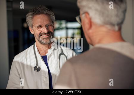 Glücklicher Arzt, der mit dem Mann im Krankenhaus spricht Stockfoto