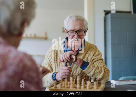 Senior-Mann spielt Schachspiel mit Frau zu Hause Stockfoto