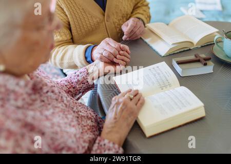 Seniorenpaar hält Hände und liest Bücher am Tisch Stockfoto