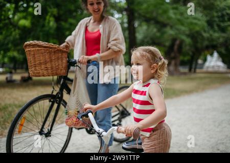 Mutter und Tochter schieben im Stadtpark Fahrräder Stockfoto