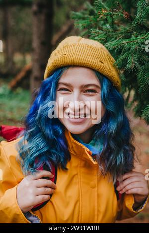 Glückliche Frau mit Strickmütze und Rucksack im Wald Stockfoto