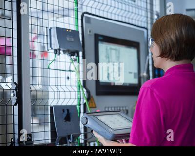 Junger Techniker, der Maschinen im Werk bedient Stockfoto