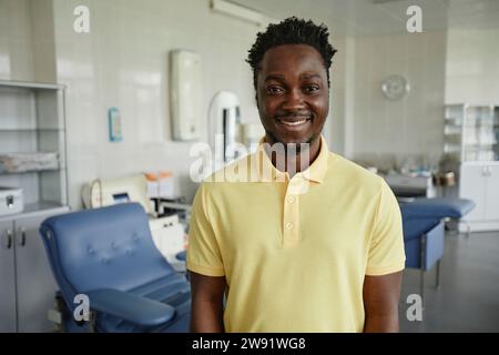 Lächelnder Mann mit gelbem Polo-T-Shirt in der Blutspendeeinrichtung Stockfoto