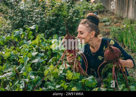 Lächelnde Frau, die im Gemüsegarten Rüben riecht Stockfoto