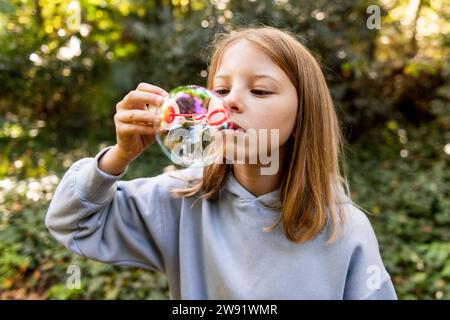Mädchen, das Blase mit Zauberstab im Park bläst Stockfoto