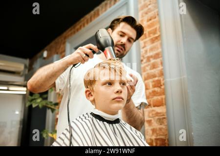 Friseur föhnt die Haare des Kunden im Salon Stockfoto