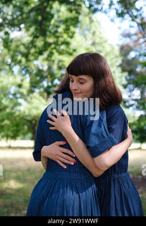 Liebe Zwillingsschwestern, die sich im Park umarmen Stockfoto