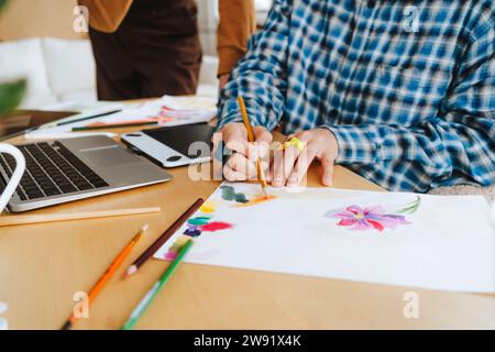 Junge Grafikdesigner-Färbung auf Papier am Schreibtisch im Büro Stockfoto