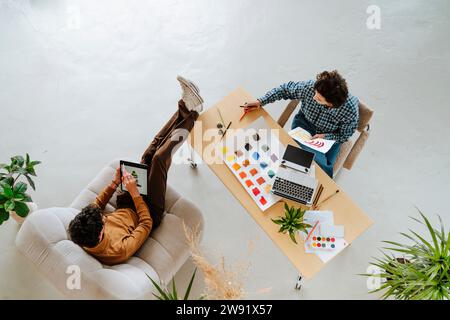 Grafikdesigner, der an drahtlosen Technologien arbeitet, sitzt am Schreibtisch im Büro Stockfoto