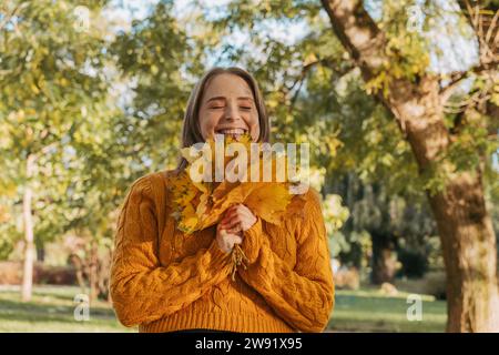 Glückliche Frau mit Ahornblättern im Herbstpark Stockfoto