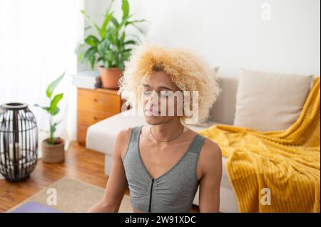 Transgender-Frau meditiert mit geschlossenen Augen zu Hause Stockfoto