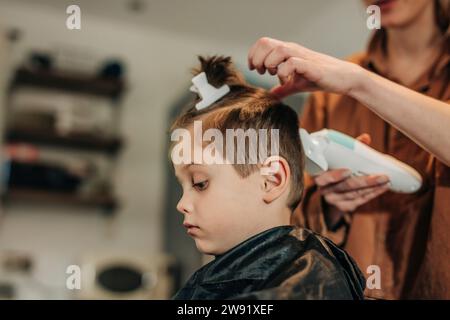 Junge, der von der Mutter zu Hause Haare schneiden lässt Stockfoto