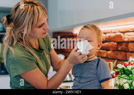 Mutter wischt dem Sohn zu Hause die Nase ab Stockfoto