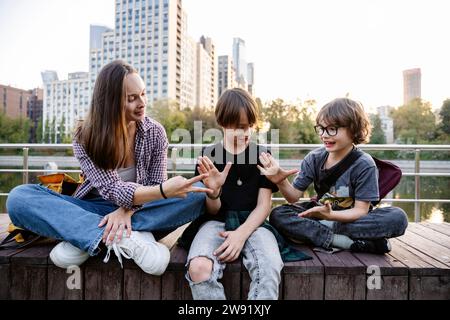 Glückliche Mutter, die mit Söhnen spielt, die auf der Bank sitzen Stockfoto