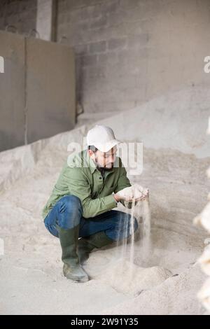 Porträt eines Bauern, der auf einem Maismehlhaufen hockt Stockfoto