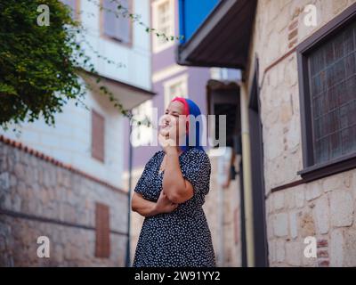 Weibliche Sommer-Altstadt Spaziergang in Antalya Türkei. Eine Frau mit bunten Haaren und Kleidern erkundet anmutig die historischen Straßen. Visuelle Sinfonie, die Vergangenheit und Gegenwart in Einklang bringt. Stockfoto