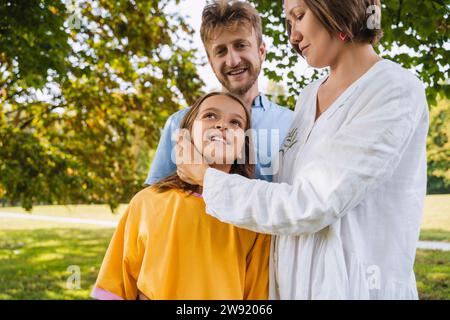 Mutter streichelt die Tochter, die mit Vater im Park steht Stockfoto