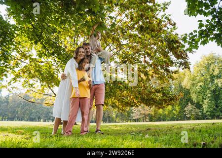 Glückliche Familie, die unter einem Baum im Park steht Stockfoto