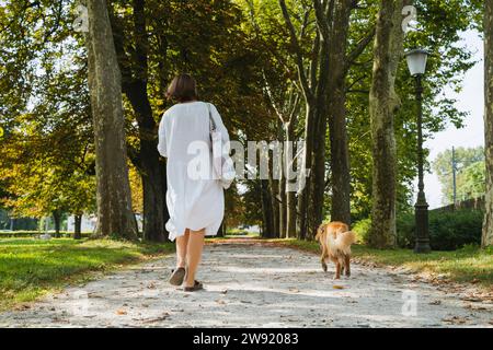 Frau, die mit Hund auf dem Fußweg im Park läuft Stockfoto