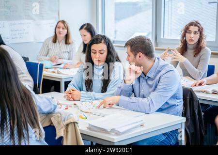 Mann erklärt dem Schüler Notizen am Schreibtisch im Klassenzimmer Stockfoto