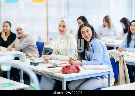 Lächelnde multiethnische Schüler beim Lernen am Schreibtisch im Klassenzimmer Stockfoto