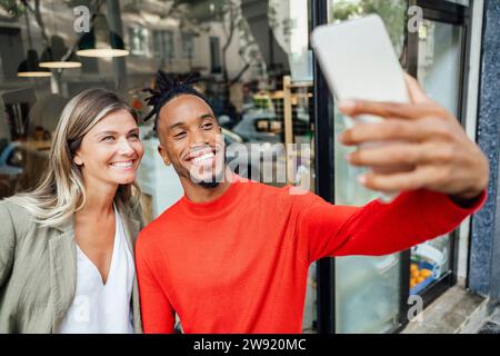 Geschäftsmann macht Selfie mit Kollegen über Tablet-PC außerhalb des Cafés Stockfoto