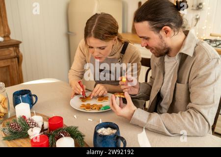 Frau, die Kekse mit Mann am Tisch in der Küche dekoriert Stockfoto