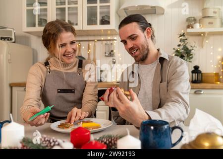 Lächelndes Paar, das Kekse in der Küche dekoriert Stockfoto