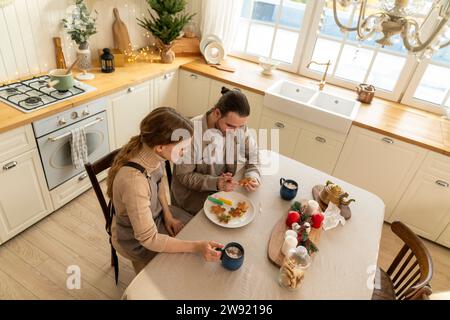 Ein paar dekorierende Kekse mit heißen Schokoladentassen auf dem Tisch in der Küche Stockfoto