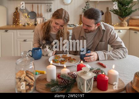 Lächelnde Frau, die eine Katze hält, während der Mann am Tisch sitzt Stockfoto