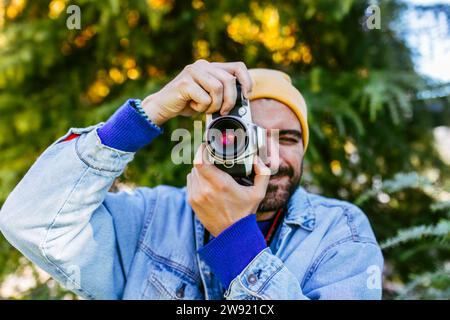 Mann fotografiert durch die Kamera vor einem Baum Stockfoto