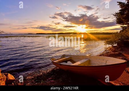 Schweden, Gavleborg County, Hedesunda, leeres Ruderboot, das bei Sonnenuntergang auf Lakeshore liegt Stockfoto