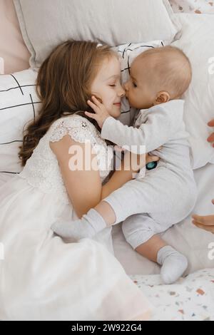 Lächelnde Schwester liegend und umarmte Bruder auf dem Bett Stockfoto