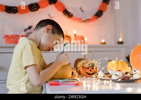 Junge, der zu Hause Kürbis mit farbigem Stift zeichnet Stockfoto