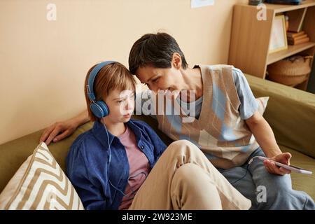 Mutter, die Musik auf dem Smartphone anschaltet, von einem Mädchen, das zu Hause Kopfhörer trägt Stockfoto