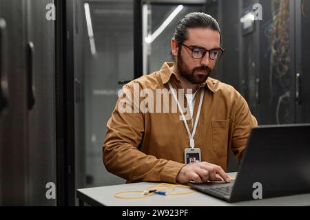 IT-Profi mit Laptop im Serverraum am Schreibtisch Stockfoto